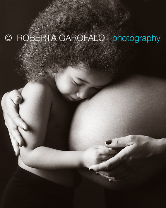 Fotografia di bambina che abbraccia il pancione della mamma